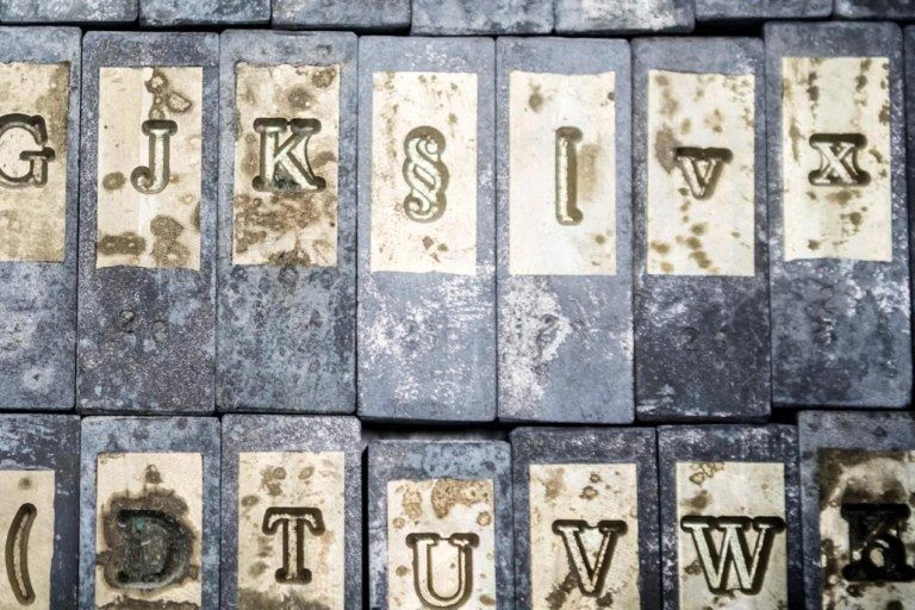 Uppercase, lowercase and punctuation marks on golden matrices on gray bricks